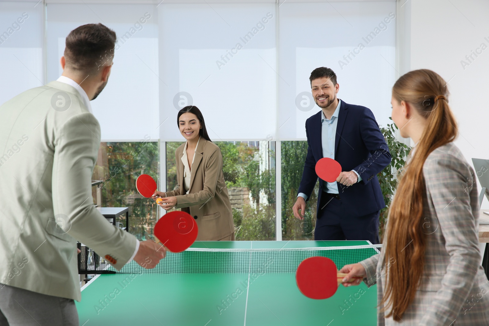 Photo of Business people playing ping pong in office