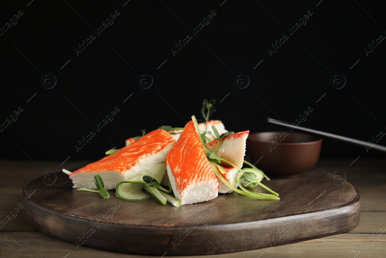 Photo of Fresh crab sticks with cucumber and soy sauce served on wooden table