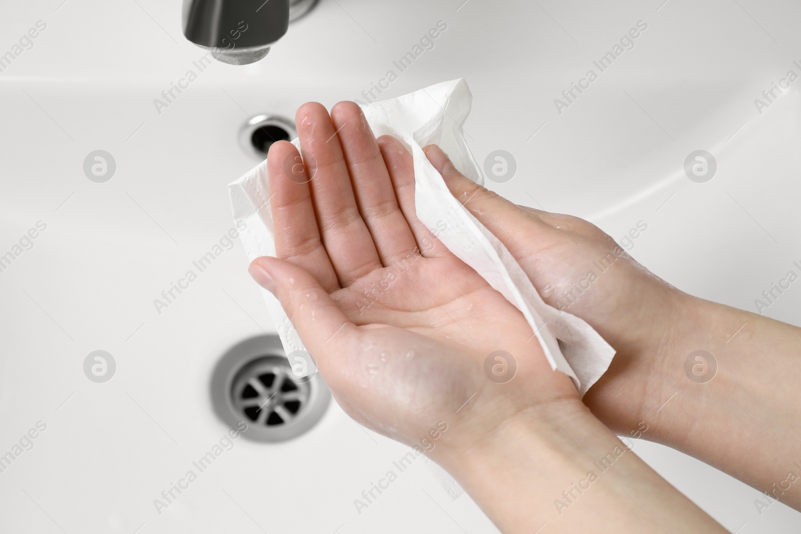 Photo of Woman wiping hands with paper towel near sink, closeup