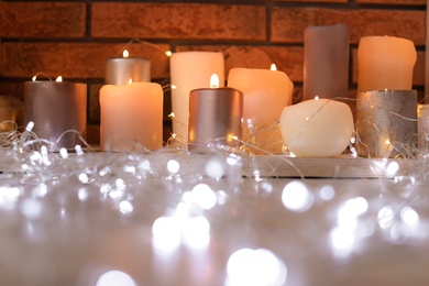 Burning candles and Christmas lights on floor indoors