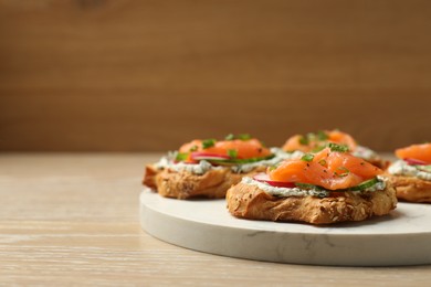 Tasty canapes with salmon, cucumber, radish and cream cheese on wooden table, space for text