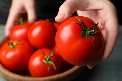 Photo of Woman with ripe tomatoes at table, closeup