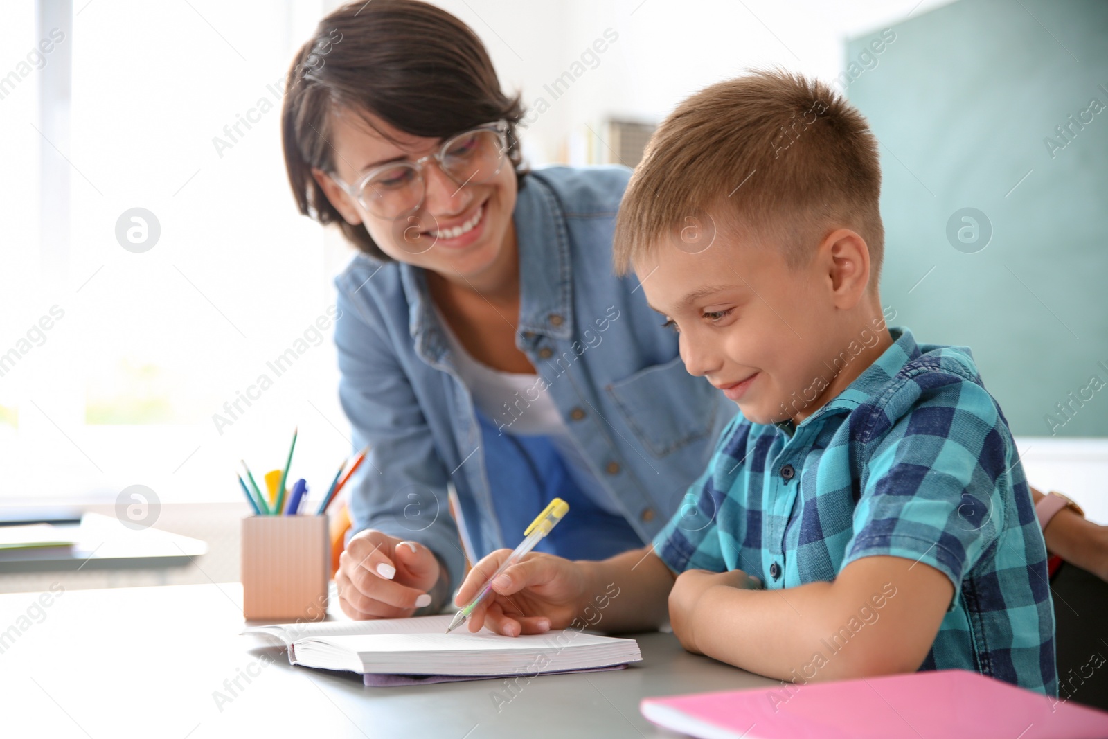 Photo of Female teacher helping child with assignment at school