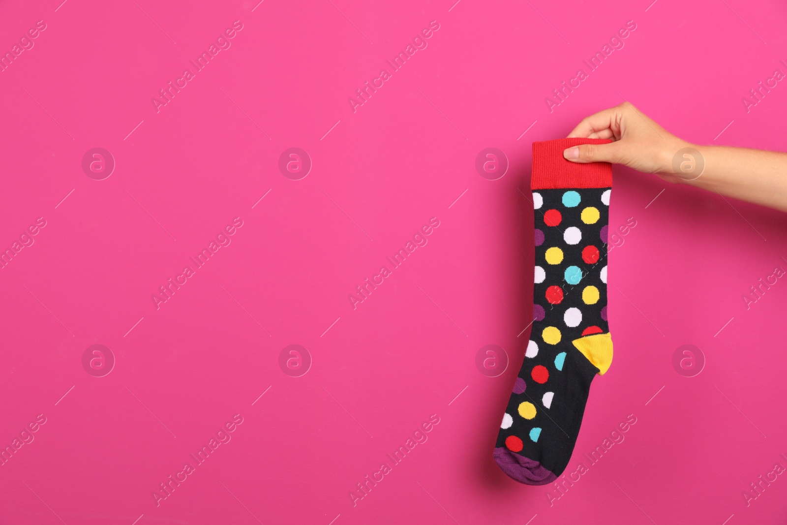 Photo of Woman holding bright sock and space for design on color background