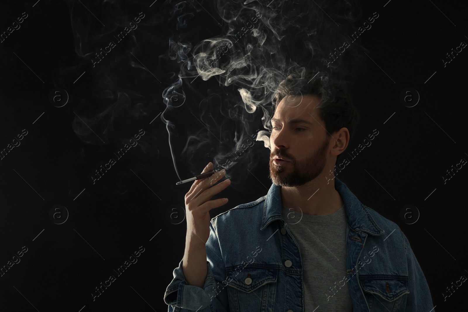 Photo of Man using cigarette holder for smoking on black background, space for text