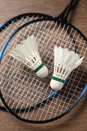 Photo of Feather badminton shuttlecocks and rackets on wooden table, top view