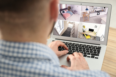 Man monitoring modern cctv cameras on laptop indoors, closeup. Home security system