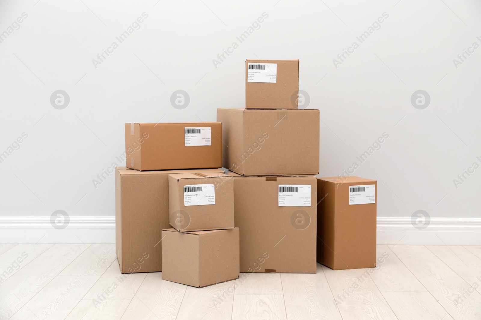 Photo of Stacked parcel boxes on floor against light wall