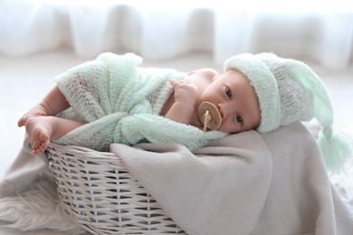 Cute newborn baby lying on plaid in basket at home