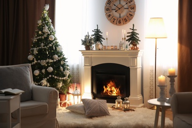 Photo of Beautiful room interior with small firs, fireplace and decorated Christmas tree