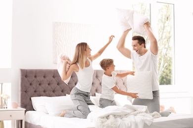 Happy family having pillow fight on bed at home