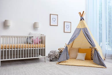 Photo of Cozy baby room interior with play tent and toys