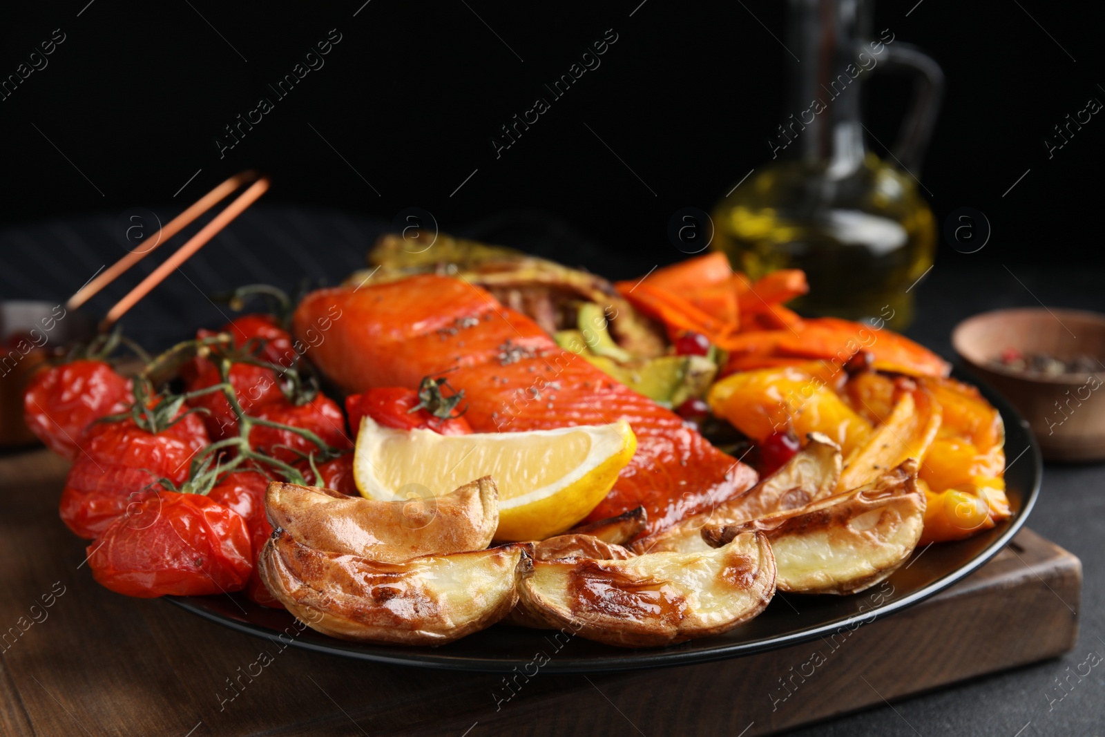 Photo of Tasty cooked salmon and vegetables served on black table, closeup. Healthy meals from air fryer