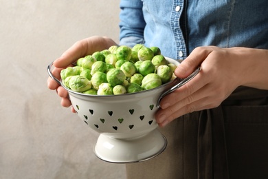 Photo of Woman holding colander with fresh Brussels sprouts, closeup