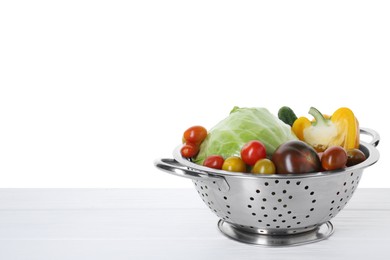 Photo of Metal colander with different vegetables on table against white background, space for text