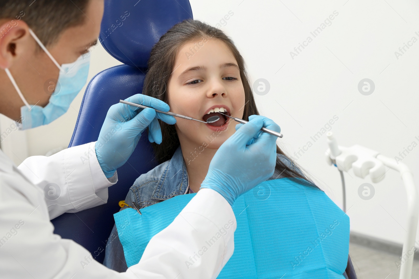 Photo of Professional dentist working with little girl in clinic