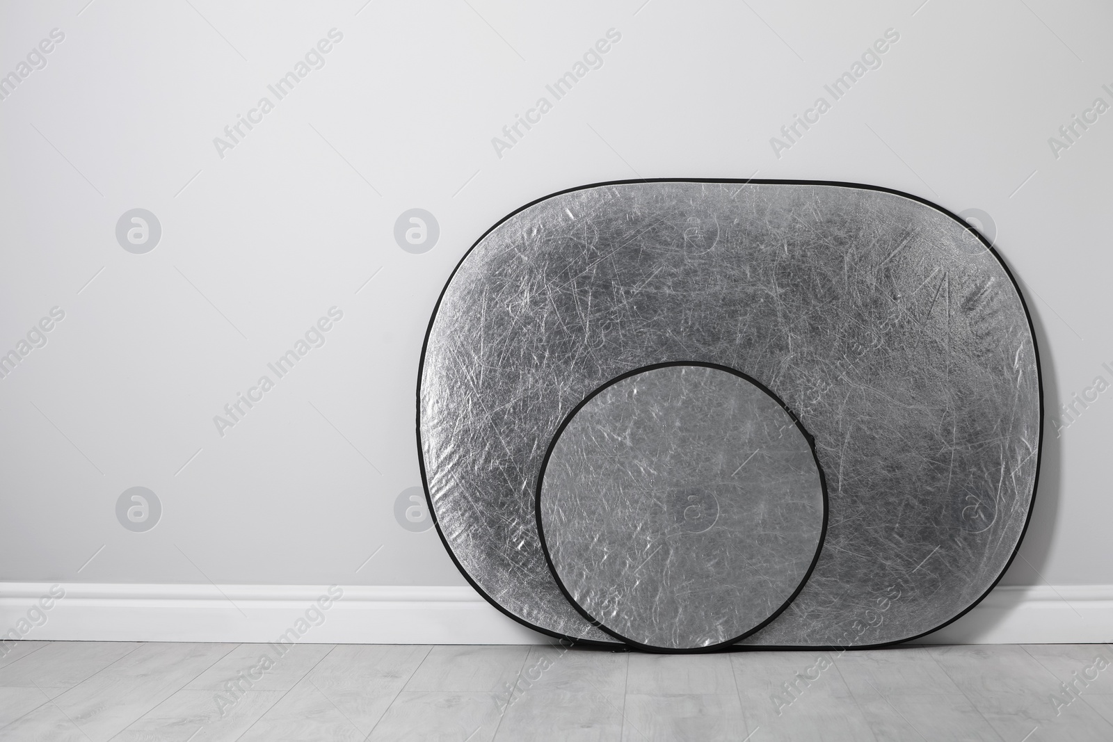 Photo of Studio reflectors near grey wall in room, space for text. Professional photographer's equipment