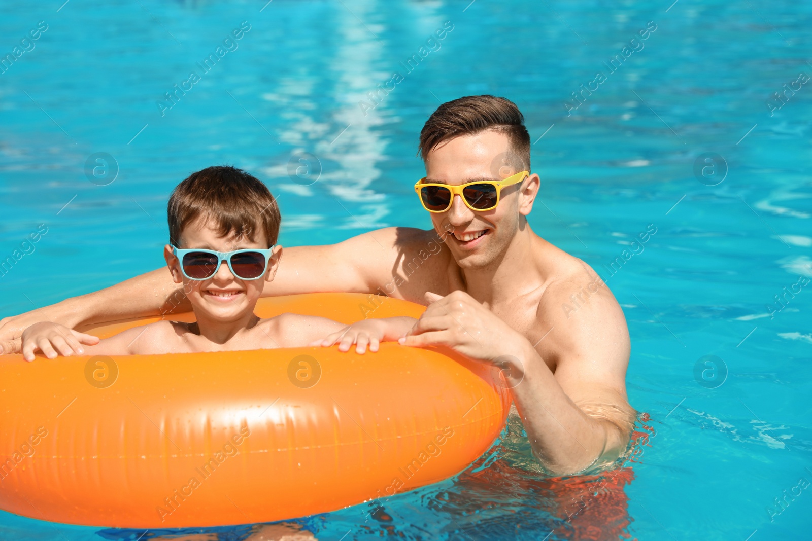 Photo of Happy father with his son in swimming pool at resort