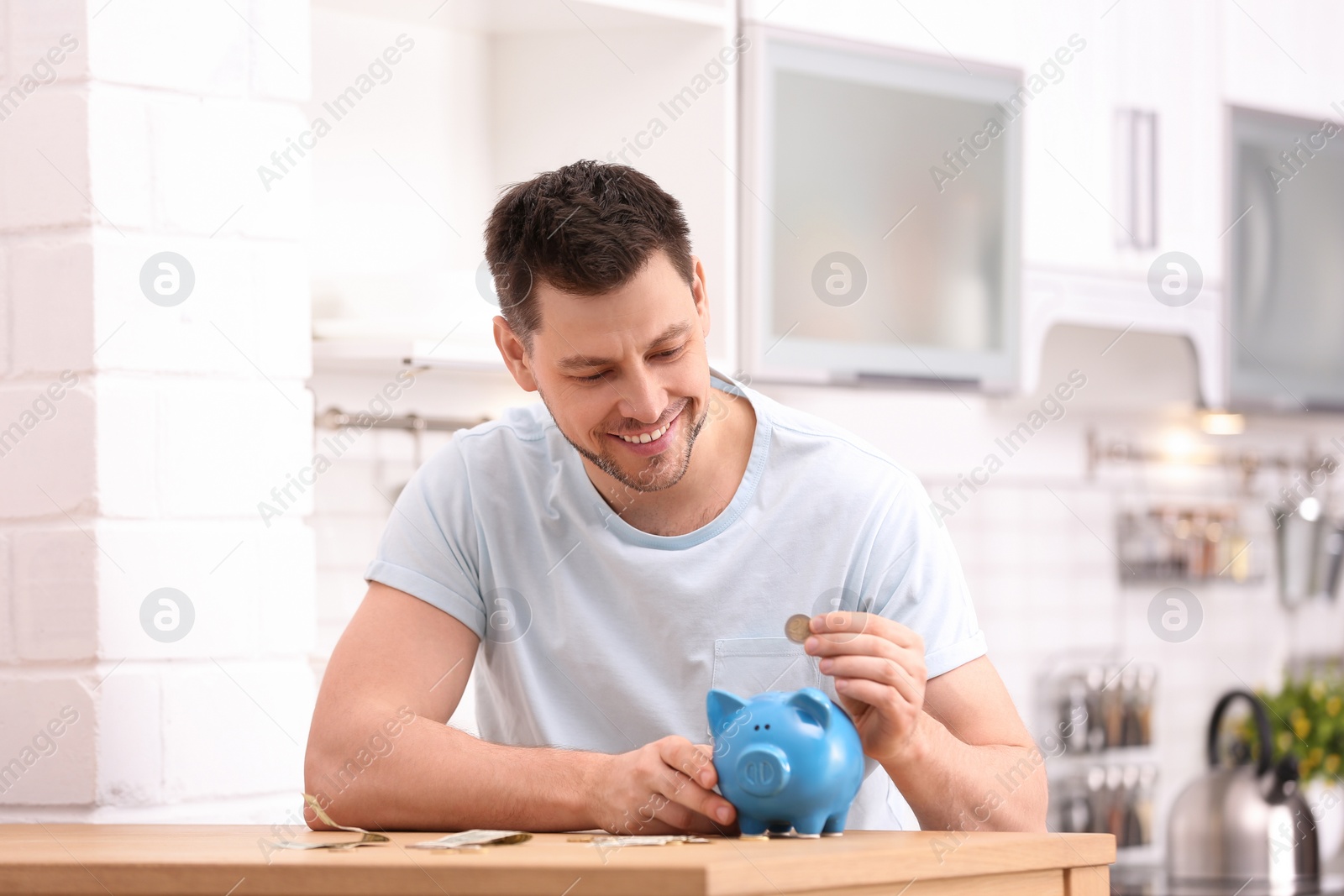 Photo of Man with piggy bank and money at home