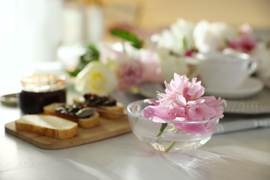 Photo of Beautiful pink peony in glass bowl on kitchen counter 