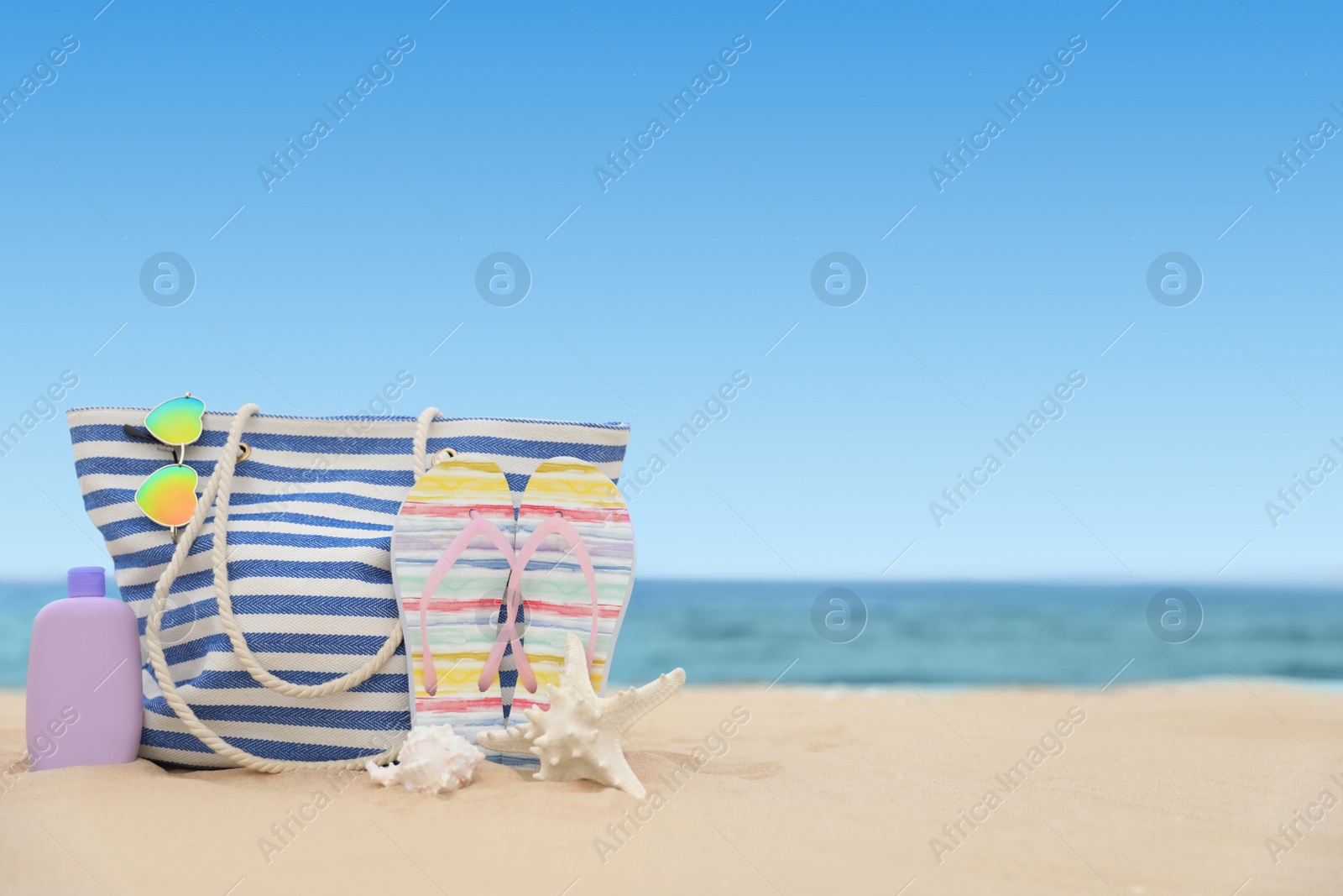 Photo of Bag and beach objects on sand near sea, space for text