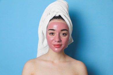 Woman with pomegranate face mask on light blue background