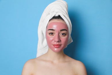 Photo of Woman with pomegranate face mask on light blue background