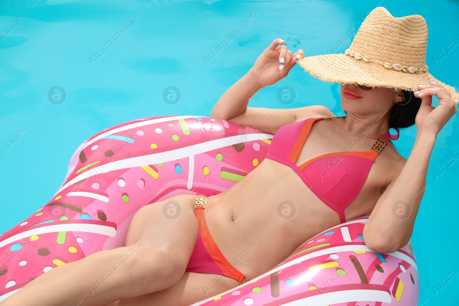 Photo of Young woman wearing stylish pink bikini on inflatable ring in swimming pool, above view