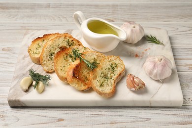 Photo of Tasty baguette with garlic, dill, rosemary and oil on white wooden table