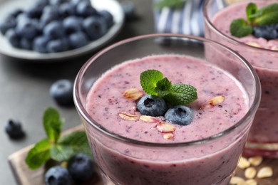 Photo of Glass of tasty blueberry smoothie with oatmeal on table, closeup