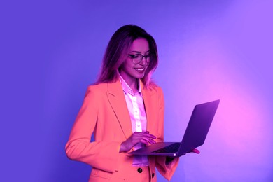 Image of Beautiful woman with laptop in neon lights