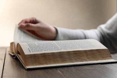 Photo of Closeup of woman reading Bible at wooden table, focus on book