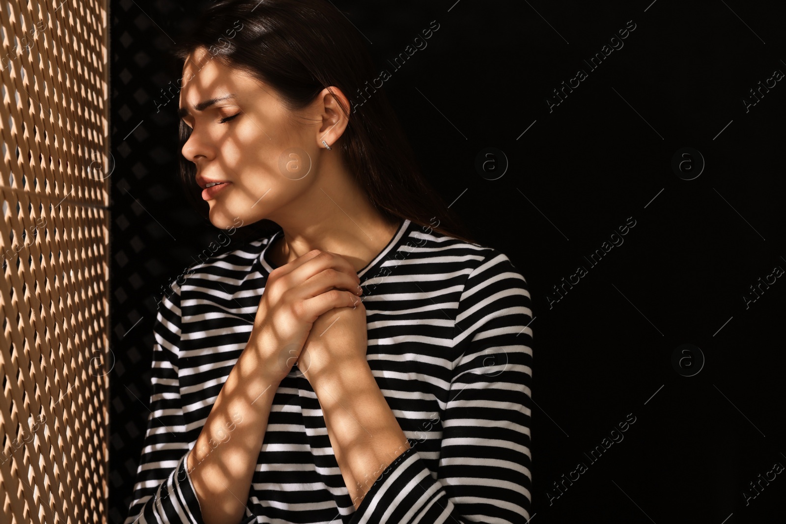 Photo of Upset woman listening to priest during confession near wooden partition in booth, space for text