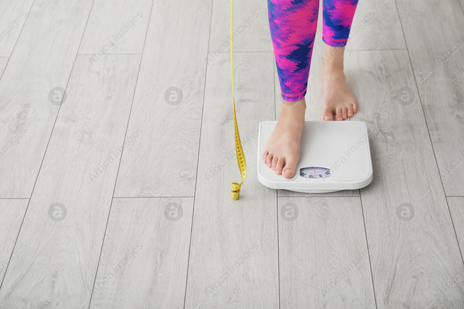 Photo of Woman with tape measuring her weight using scales on floor. Healthy diet