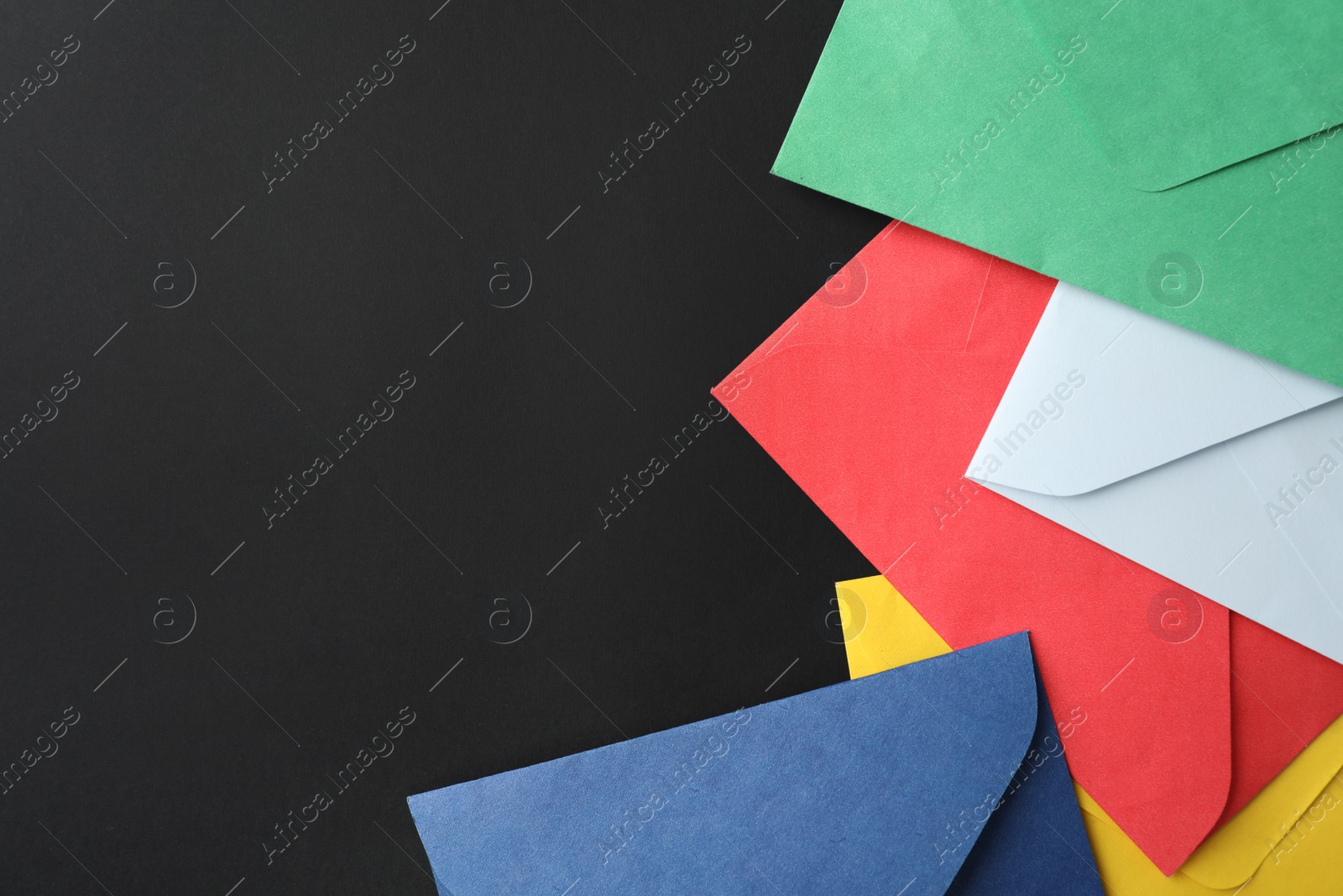 Photo of Colorful paper envelopes on black background, flat lay. Space for text