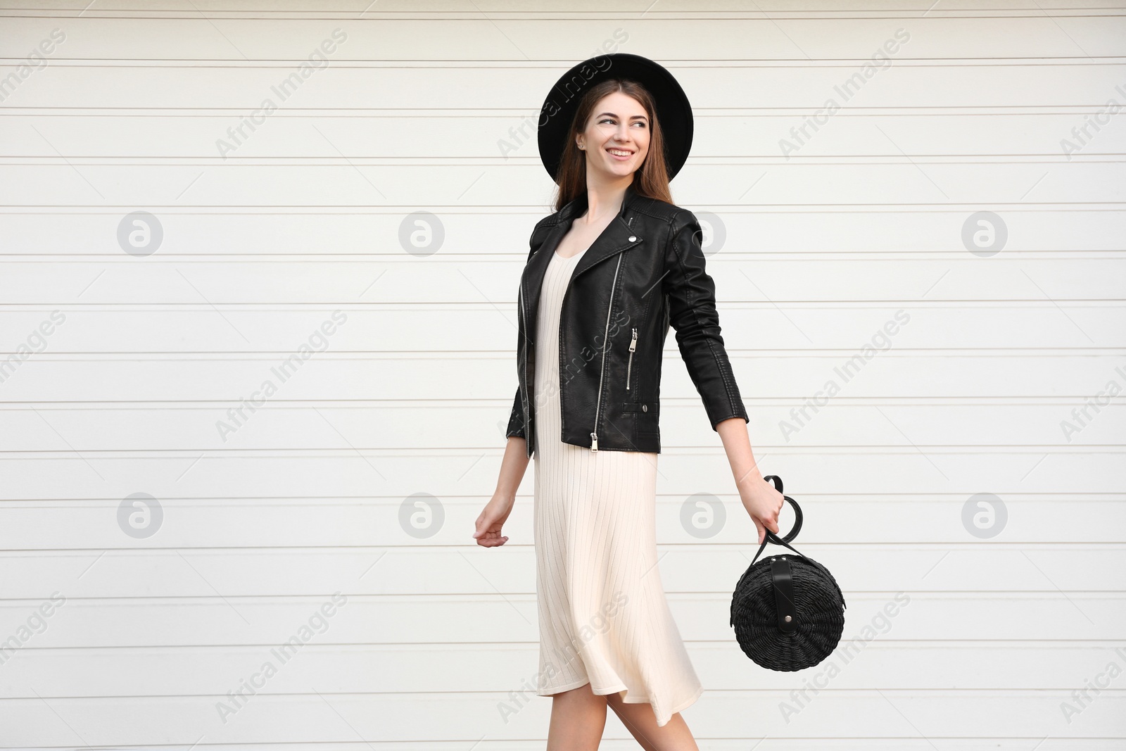 Photo of Beautiful young woman with stylish handbag near white wall