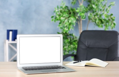 Photo of Modern laptop and notebook with pen on wooden table in office. Space for text