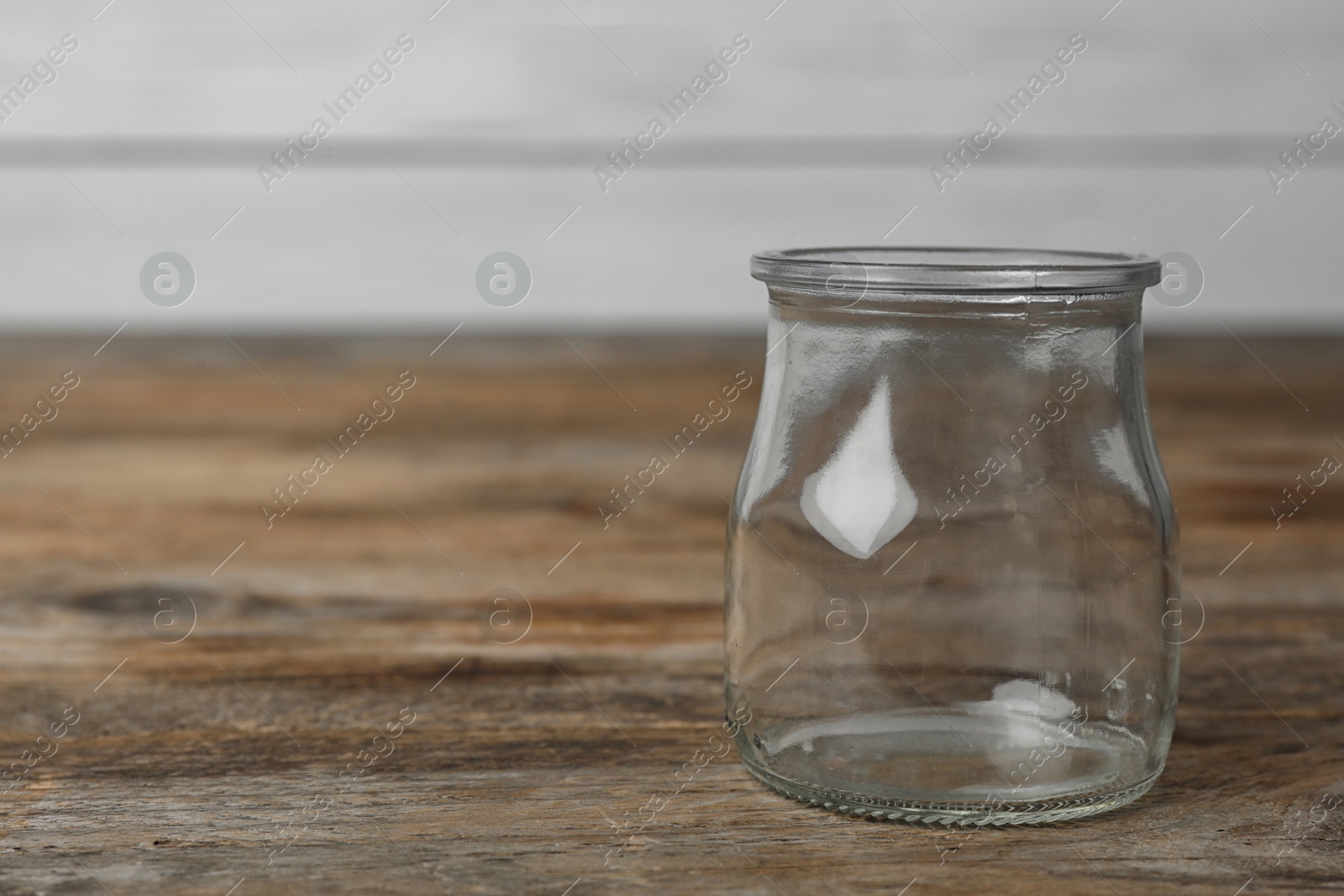 Photo of Empty glass jar on wooden table, space for text