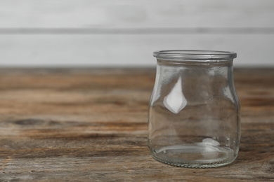 Photo of Empty glass jar on wooden table, space for text