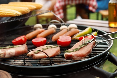 Cooking meat, sausages and vegetables on barbecue grill outdoors, closeup