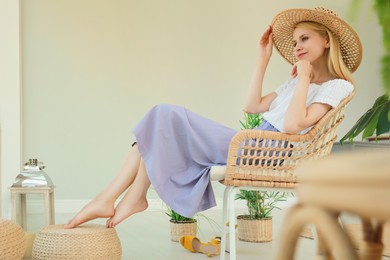 Photo of Woman with straw hat sitting in armchair at indoor terrace