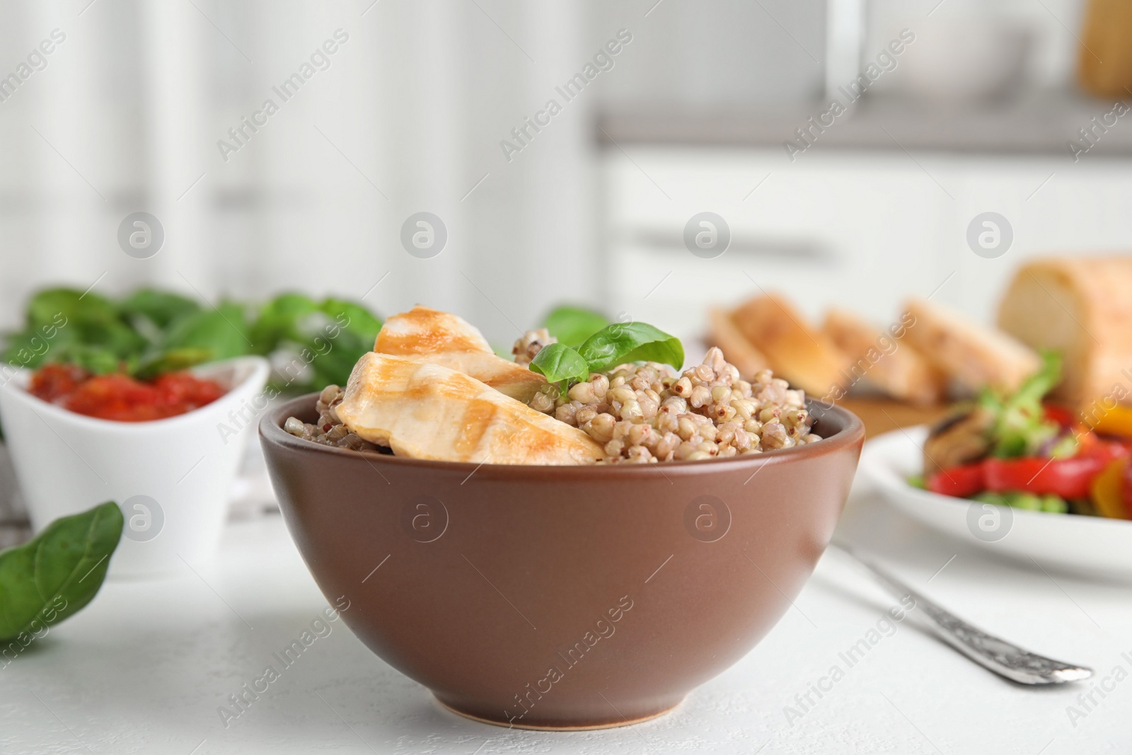 Photo of Tasty buckwheat porridge with meat on white table indoors