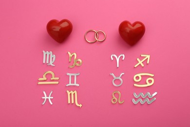 Zodiac compatibility. Signs, wedding rings and red hearts on pink background, flat lay