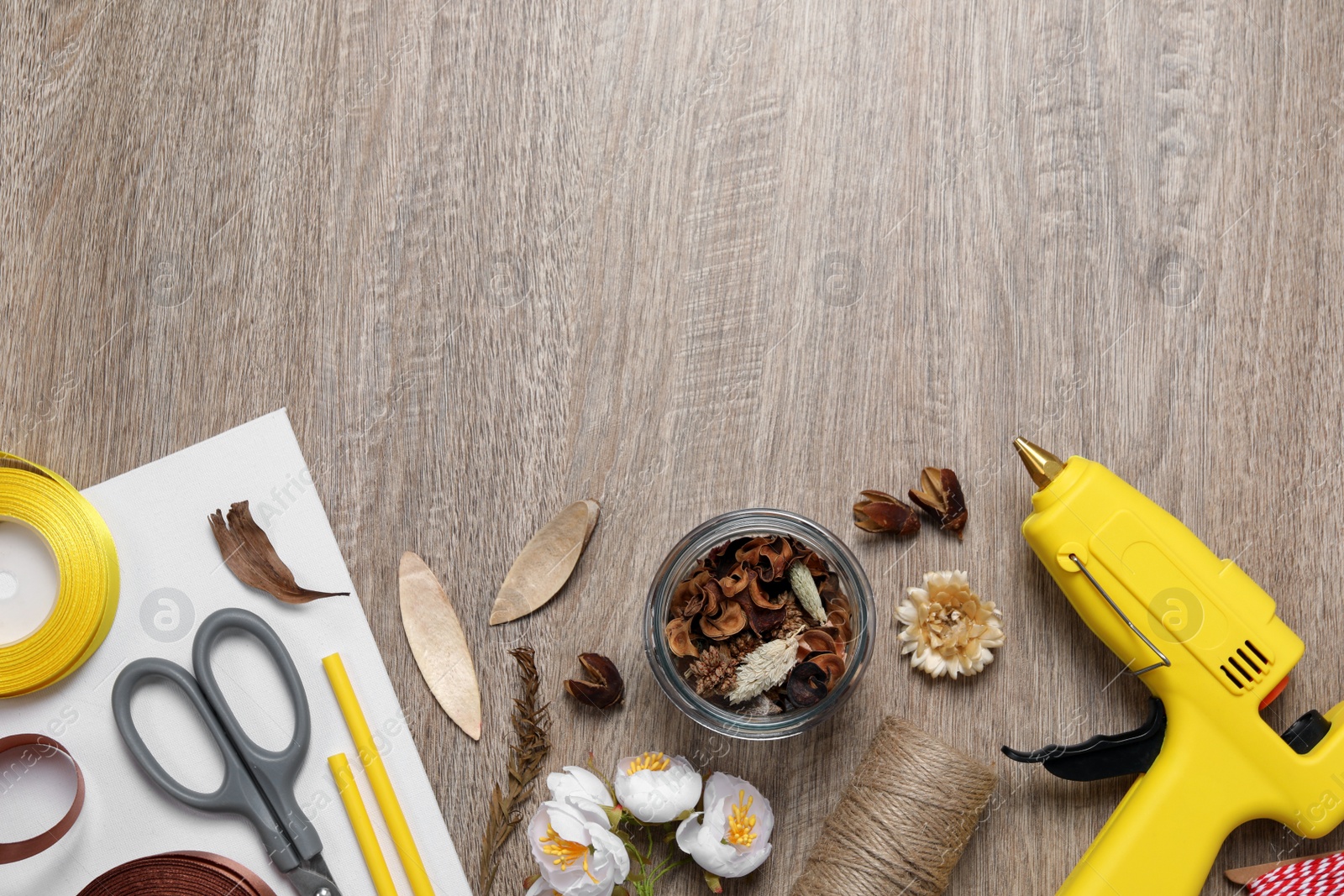 Photo of Hot glue gun and handicraft materials on wooden table, flat lay. Space for text