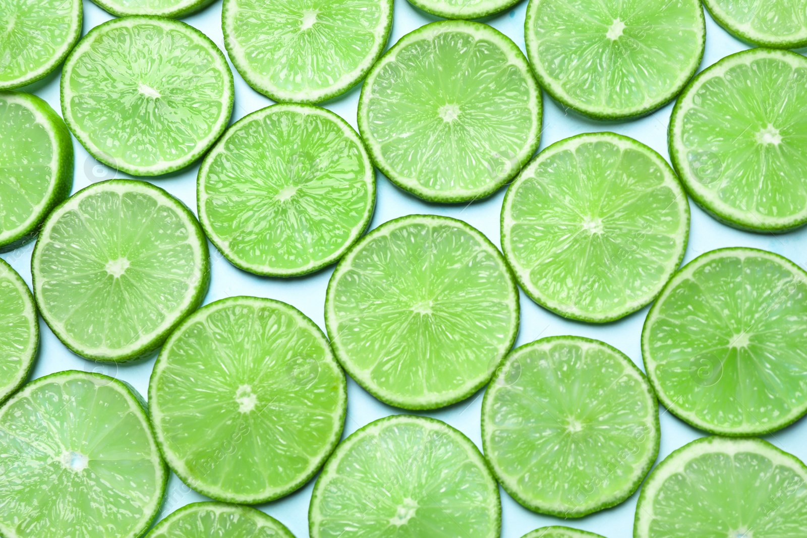 Photo of Juicy fresh lime slices on light blue background, flat lay