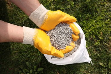 Photo of Woman with fertilizer on green grass outdoors, top view