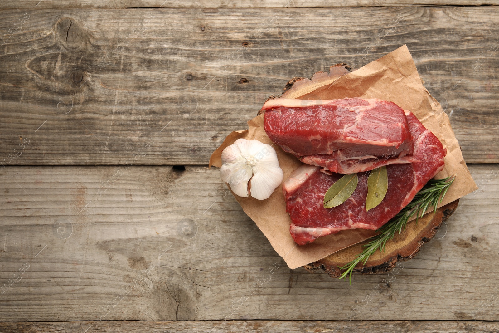 Photo of Pieces of raw beef meat and spices on wooden table, top view. Space for text