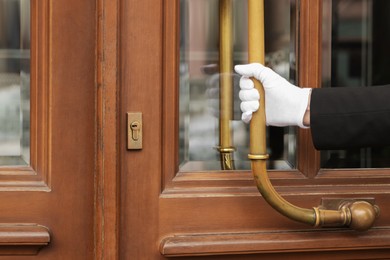 Photo of Butler in suit and white gloves opening hotel door, closeup. Space for text