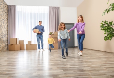 Photo of Happy family and pile of moving boxes in their new house