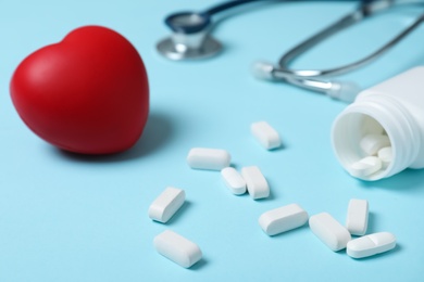Photo of Red heart and pills on color background. Cardiology concept